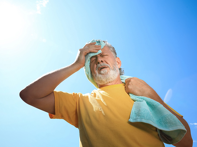 Ein älterer Mann in der Sonnenhitze hält sich die schweißbedeckte Stirn.