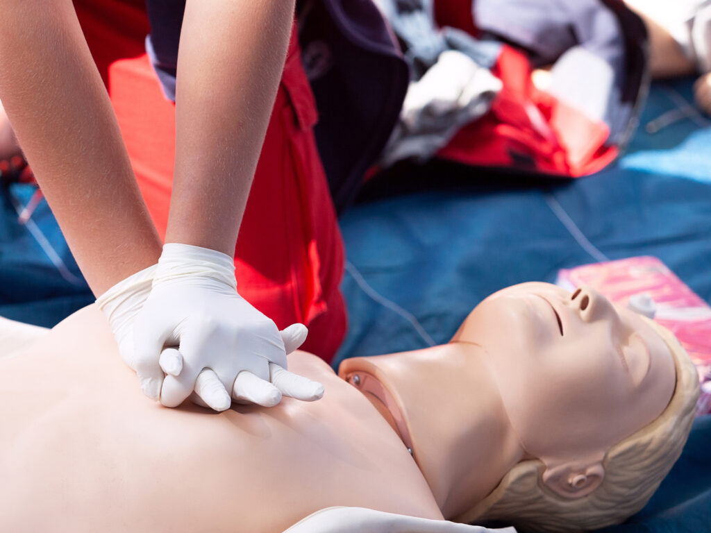Eine Person trainiert die Herzdruckmassage an einer Puppe.